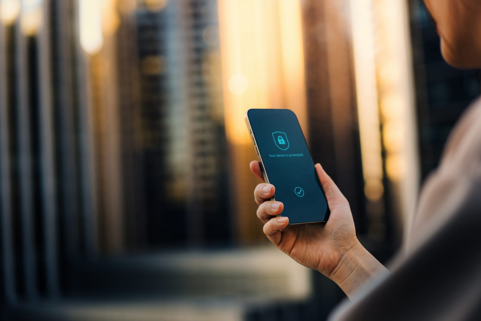 A hand holding a phone with a lock on its screen, server racks out of focus behind it.